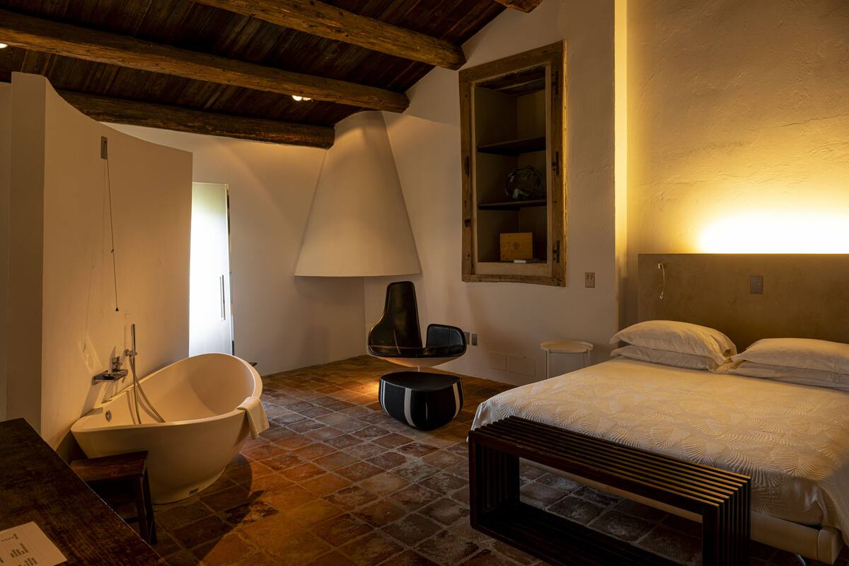 A bedroom with a large bed, a bathtub, and a chair.