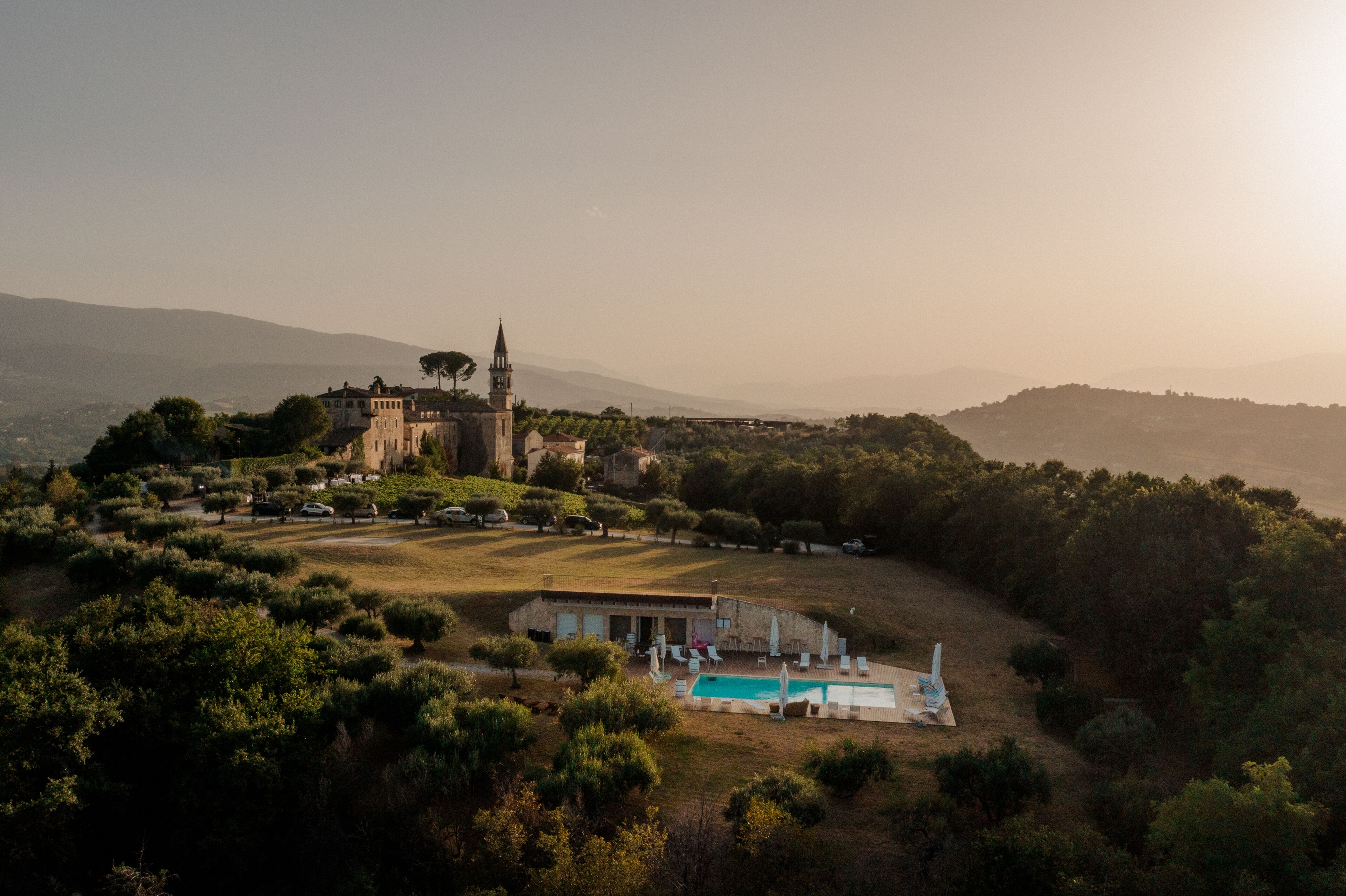 A large estate with a swimming pool, a small building, and a church with a tall tower.