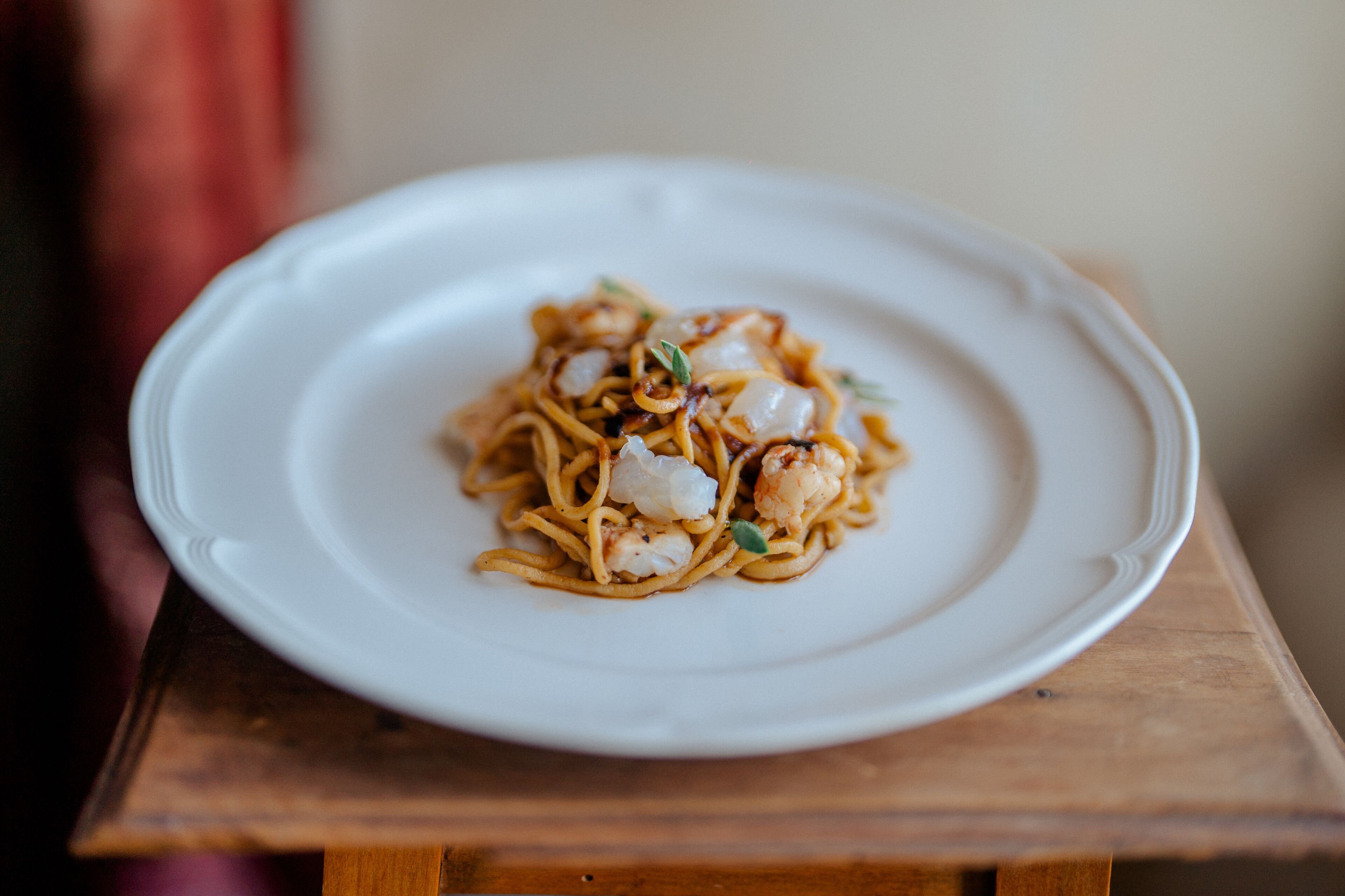 Une assiette de nouilles aux crevettes, servie dans une assiette blanche.