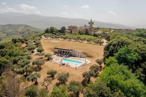 Una amplia villa con piscina, rodeada de olivos y vistas a montañas distantes.