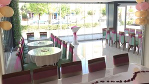 A dining area with round tables and chairs, decorated with pink and yellow balloons. - Ayvazali Hotel (Bergama)
