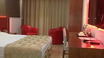 Quarto de hotel com duas camas, uma mesa de trabalho e uma televisão de tela plana, além de uma cadeira vermelha.