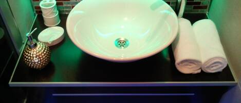 A bathroom with a white sink, a towel warmer, and a decorative pineapple-shaped container.