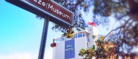A sign for a museum with a hotel in the background.