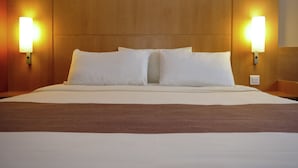 A hotel room with a large bed, two wall-mounted lamps, and a wooden headboard. - ibis Bulle La Gruyere (Bulle)