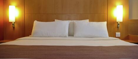 Una habitación de hotel con una cama grande, dos lámparas de pared y un cabecero de madera.