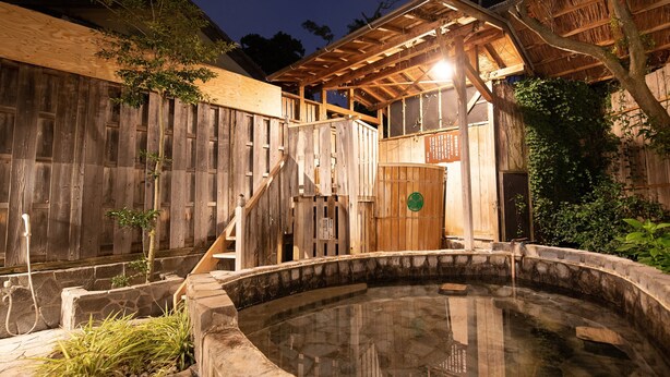 A traditional wooden bathhouse with a stone hot spring, wooden stairs, and a thatched roof structure. - Shirahamakan (Shirahama)