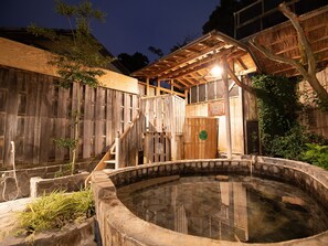 A traditional wooden bathhouse with a stone hot spring, wooden stairs, and a thatched roof structure. - Shirahamakan (Shirahama)
