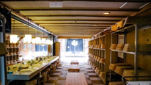 A long, narrow room with multiple sinks and benches, wooden flooring, and shelves with baskets. - Shirahamakan (Shirahama)