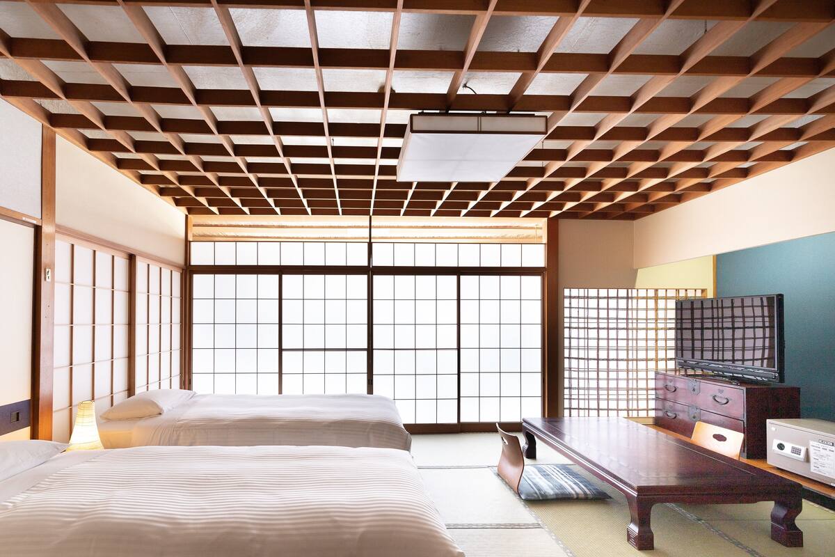 A traditional Japanese room with tatami flooring, a low wooden ceiling, and sliding doors.