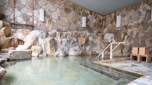 A stone-walled indoor pool with clear water, wooden steps, and benches. - Shirahamakan (Shirahama)