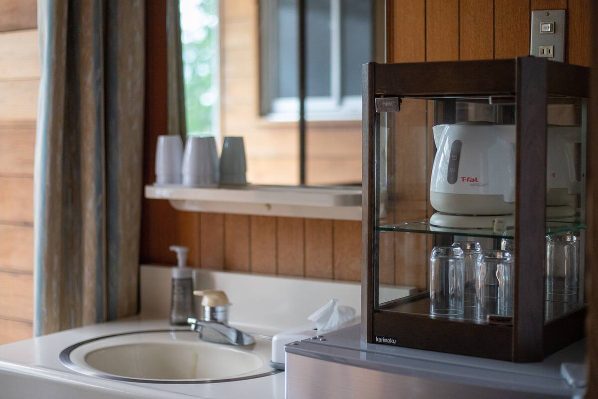 A bathroom with a sink, mirror, and a coffee machine in a cabinet.
