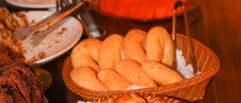 Una mesa de buffet con diversos alimentos, incluyendo pan y repostería.