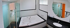 A modern bathroom with a freestanding bathtub, a sink, and a large mirror. - Bernal Hotel (Ituiutaba)