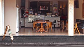 The exterior of Tintorettò Café & Restaurant with a clear glass front, wooden furniture inside, and a signboard outside. - Bernal Hotel (Ituiutaba)