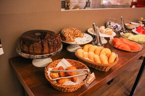 Een buffet met diverse soorten eten, zoals taarten, gebak en brood.