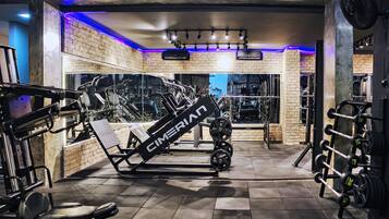 A gym with exercise equipment, a brick wall, and a ceiling fan.