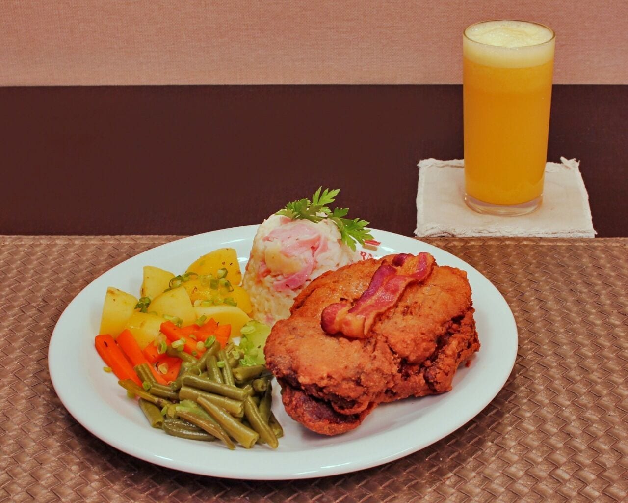 Un plato de comida con un vaso de jugo de naranja sobre una mesa.