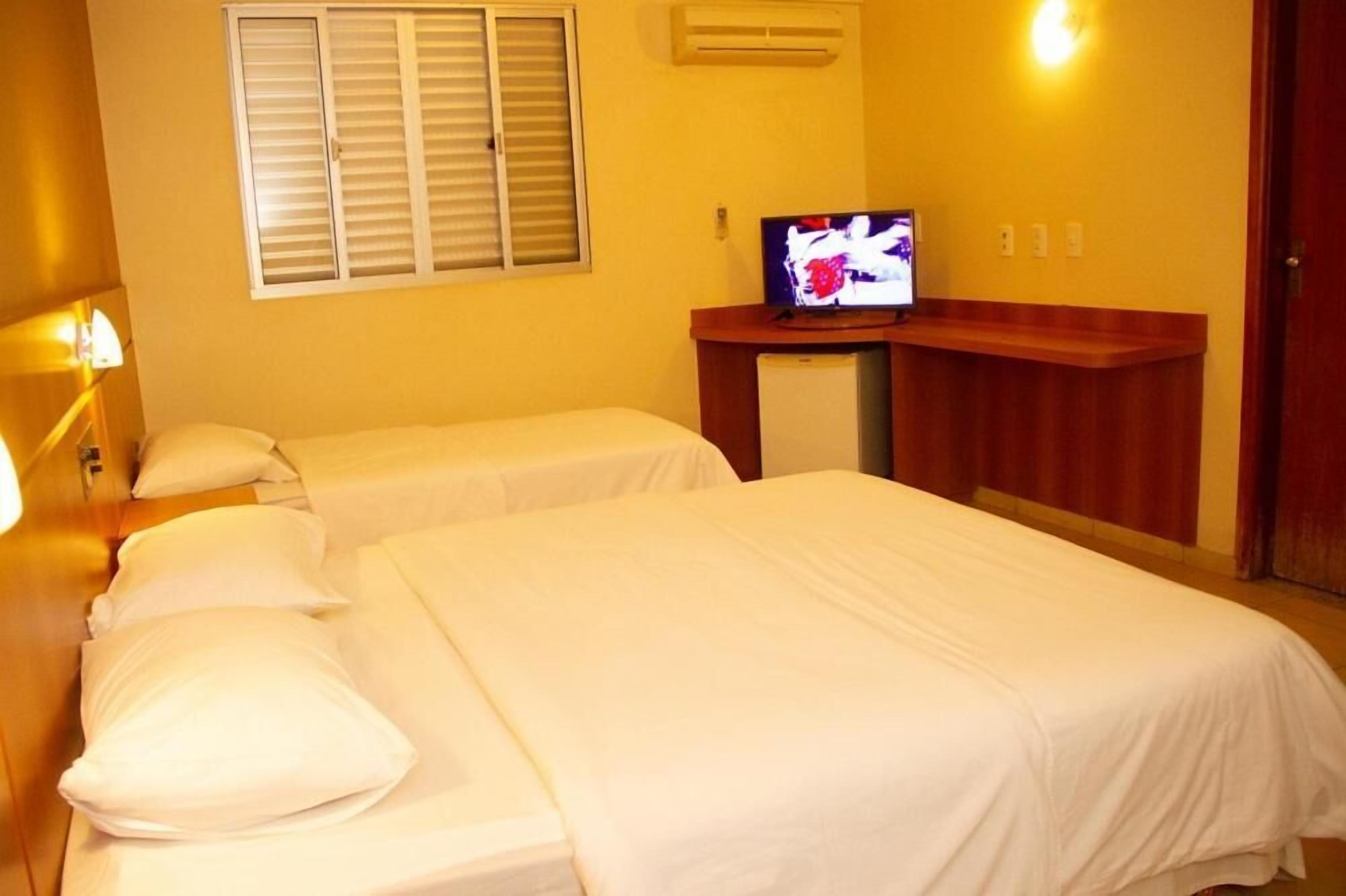 A hotel room with two beds, a television, and a small desk.