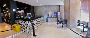 A modern hotel lobby with a reception desk, seating area, and exercise equipment. - Bernal Hotel (Ituiutaba)