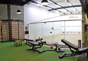A gym with exercise equipment, a bench, and a wall with a Bernal logo. - Bernal Hotel (Ituiutaba)