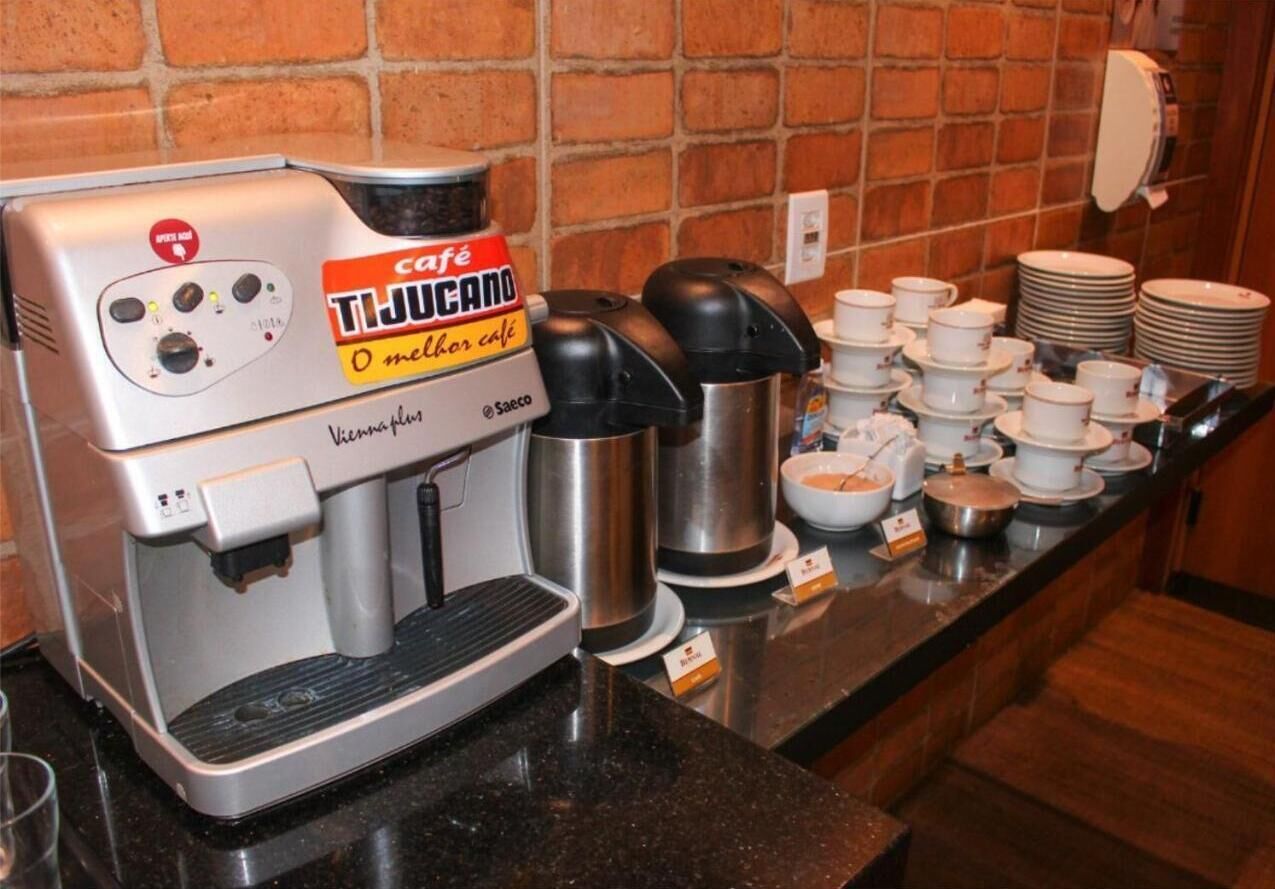 A café coffee machine with multiple coffee dispensers and a variety of coffee cups and saucers on the counter.