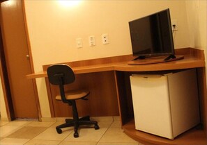 A compact office space with a desk, a chair, and a small refrigerator. - Bernal Hotel (Ituiutaba)