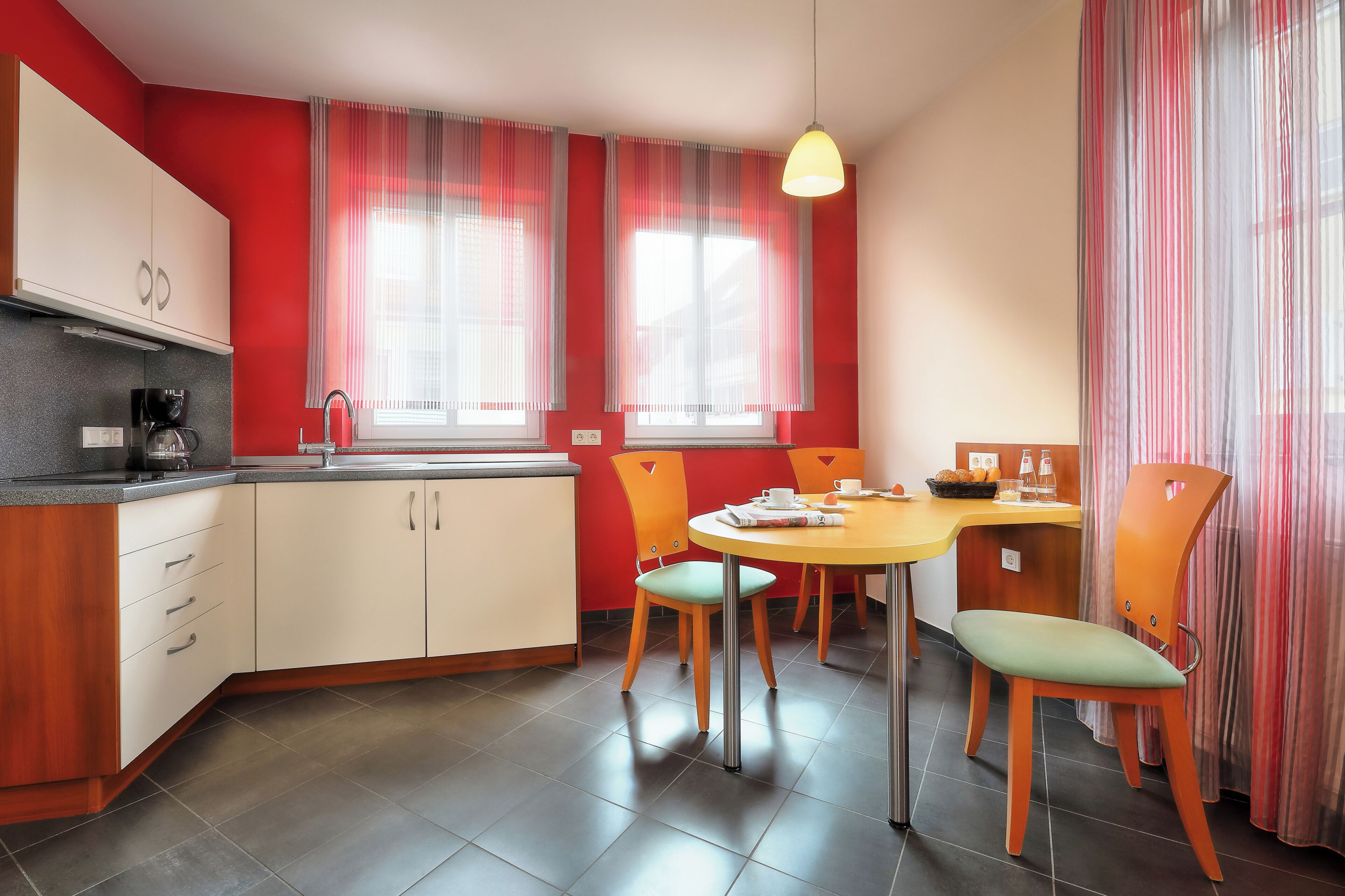 Una cocina moderna con comedor, que incluye un lavamanos, armarios y una mesa con sillas.