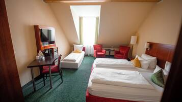 A hotel room with two beds, a desk with a chair, a TV, and a small table.