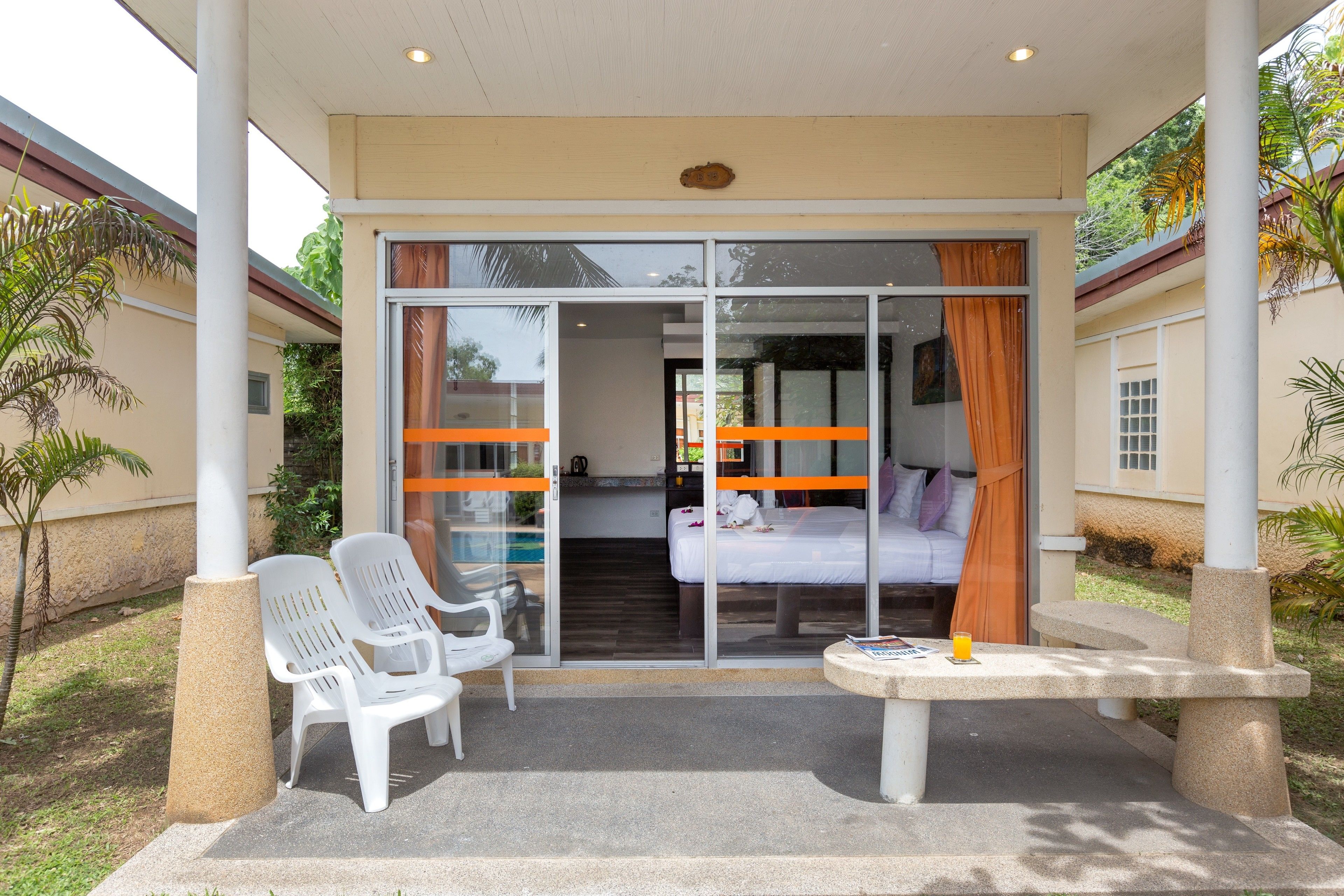 A room with a bed, a glass door, and a small table with a drink.