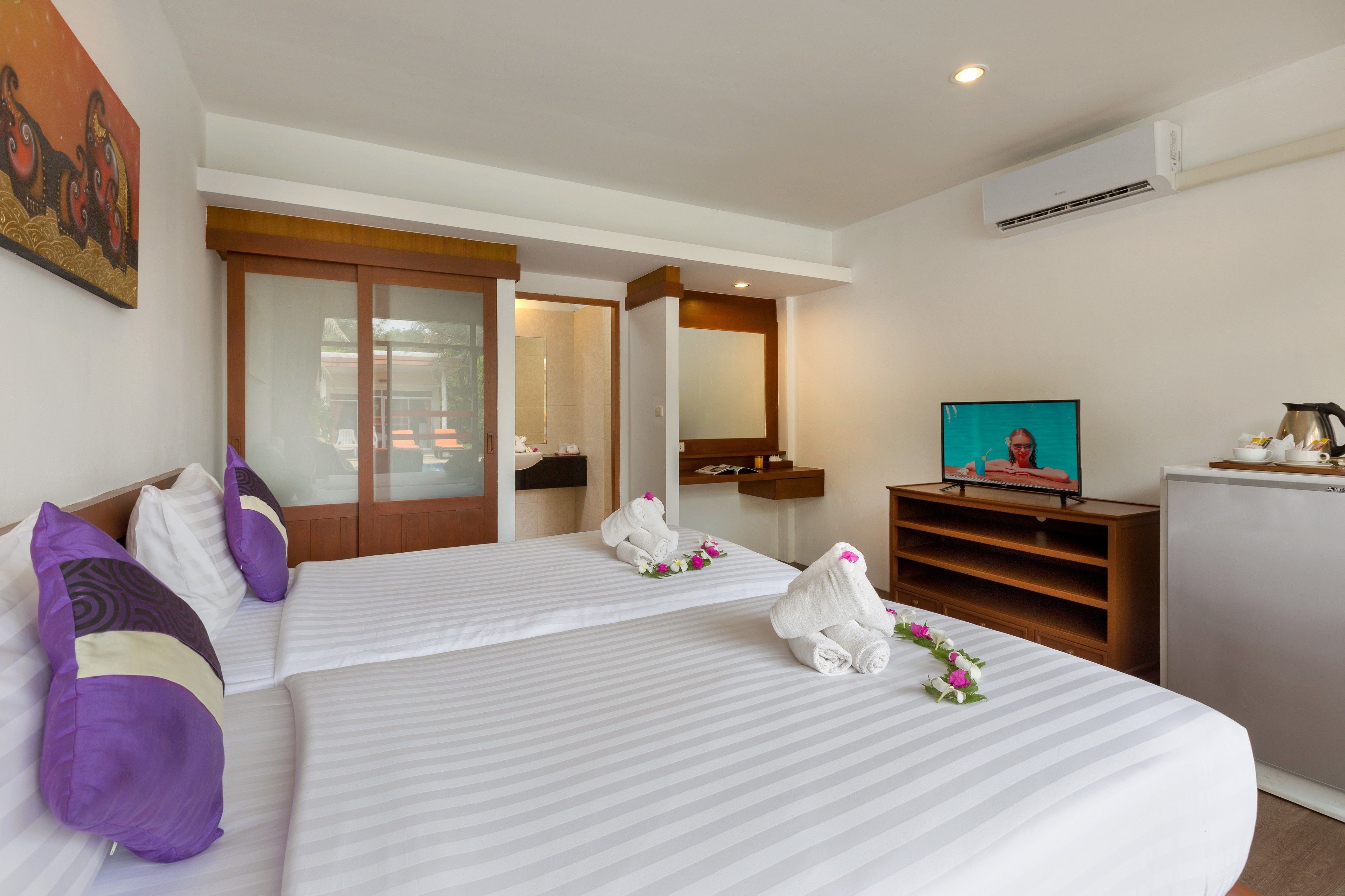 A hotel room with two beds, a television, a minibar, and a sliding door leading to a bathroom.
