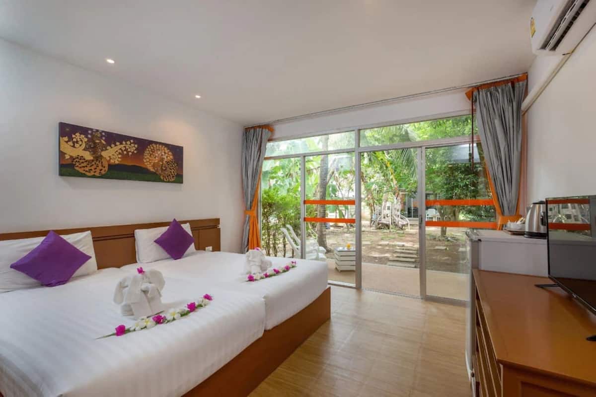 A hotel room with a bed, a desk, a TV, and a large window with curtains.