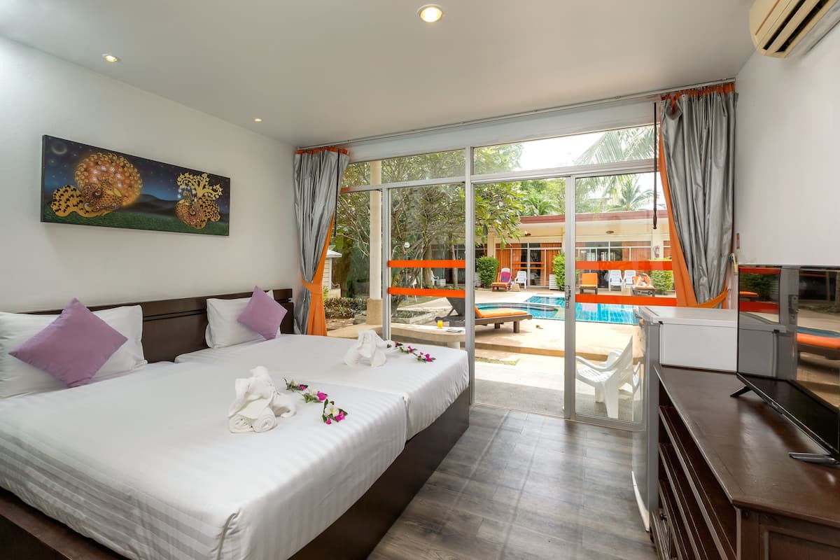 A hotel room with a large bed, two pillows, a painting, a TV, and a view of an outdoor swimming pool.