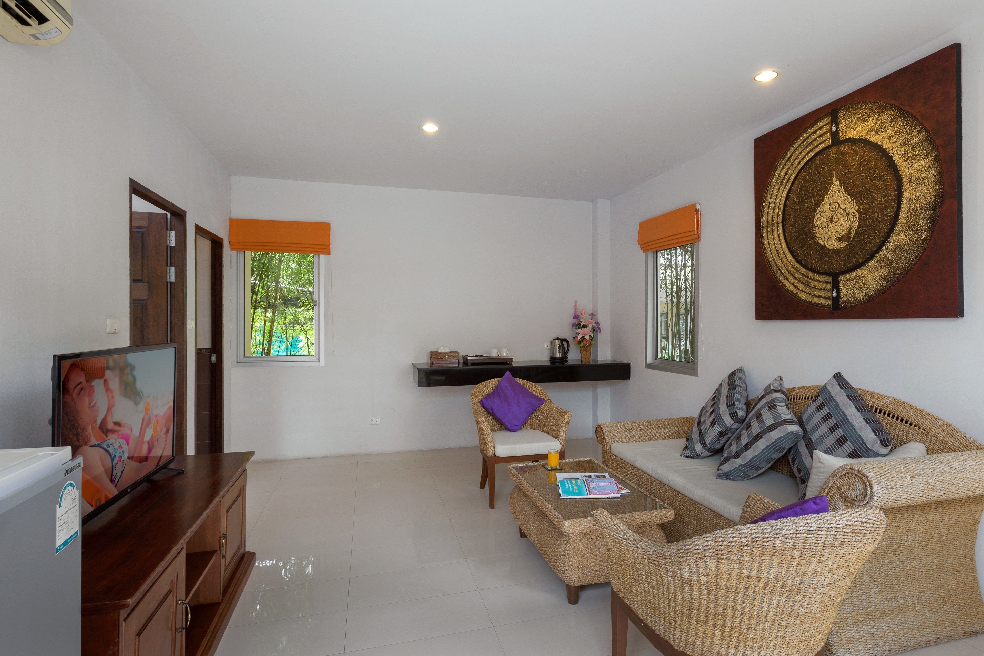 A living room with a television, wicker furniture, and a decorative wall piece.