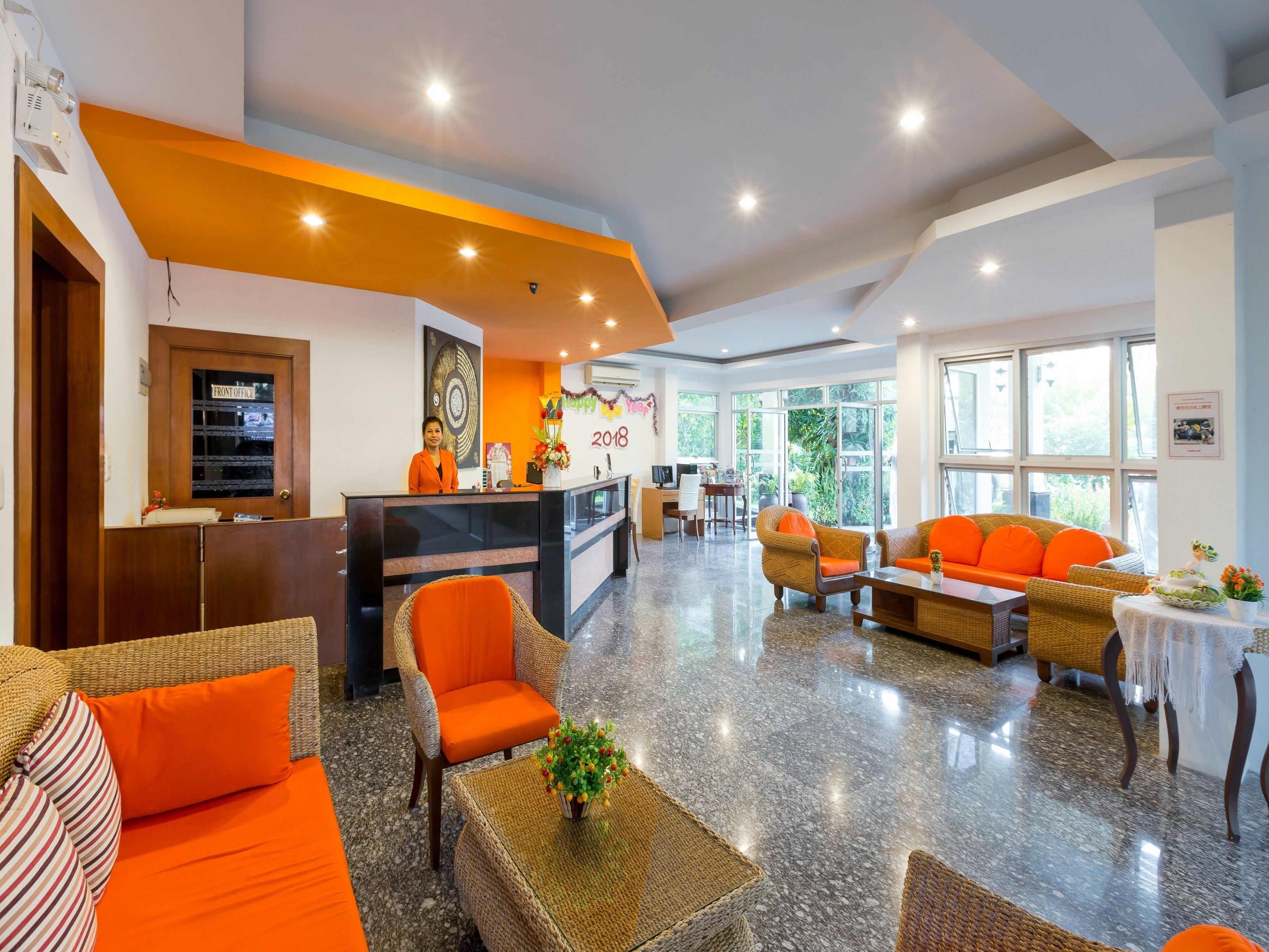Un vestíbulo de hotel con mostrador de recepción, zona de estar y grandes ventanales.