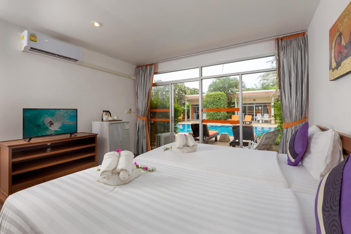 A hotel room with a large bed, a television, a desk, and a view of a swimming pool.