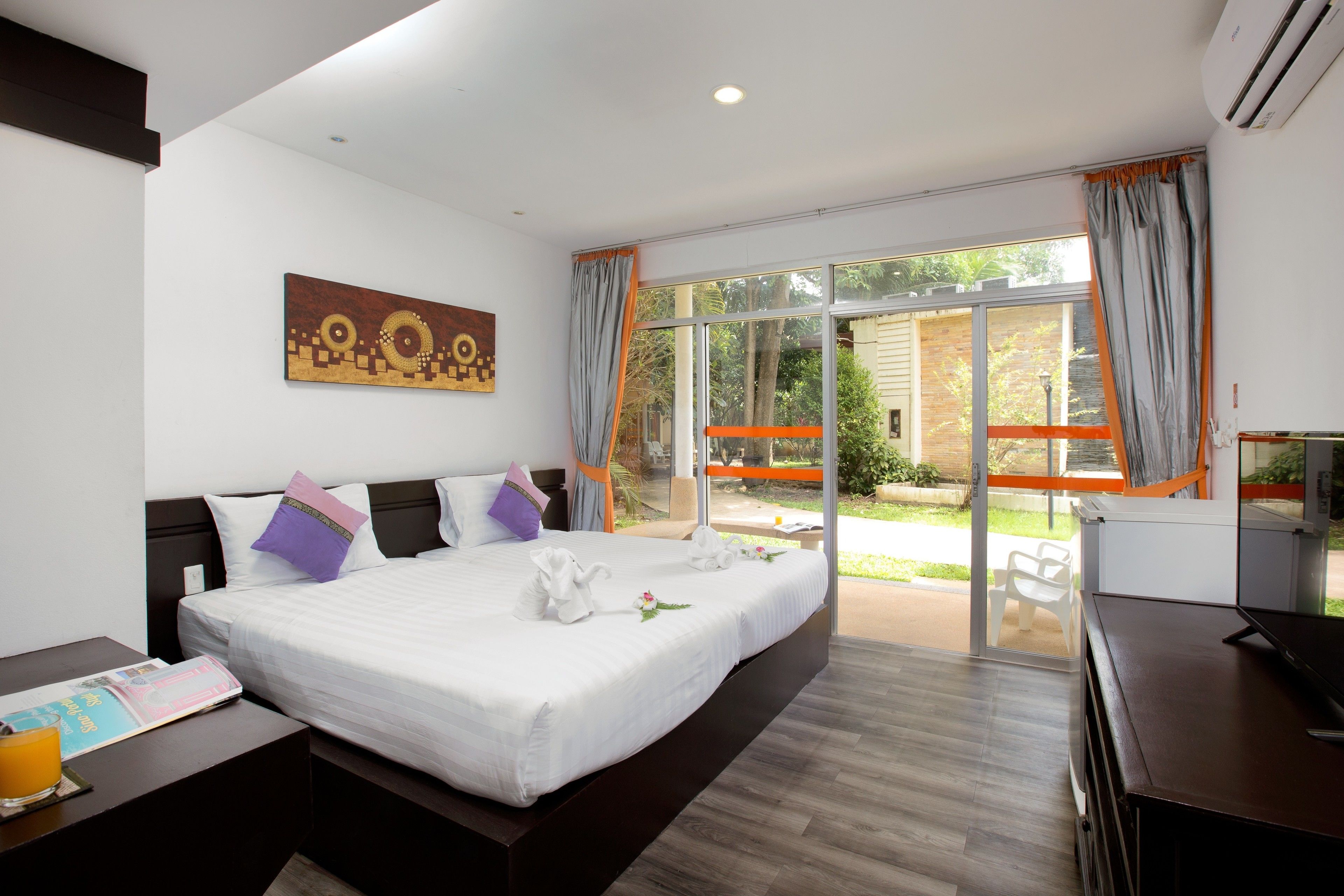 A modern hotel room with a large bed, a desk, and a view of the outdoor area.