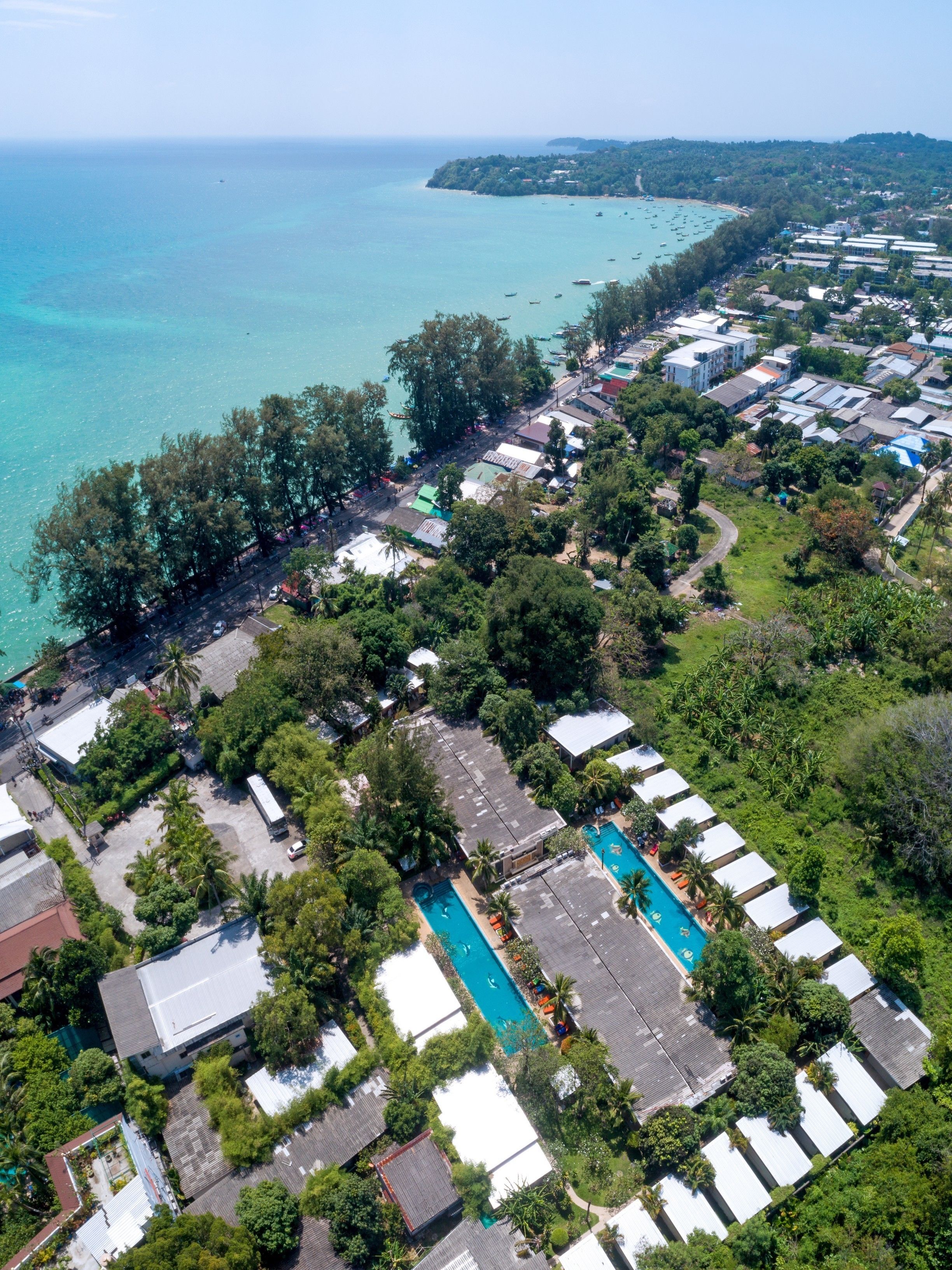 Ein Luftbild eines Küstenresorts mit Schwimmbad, mehreren Bungalows und einem Strand im Hintergrund.