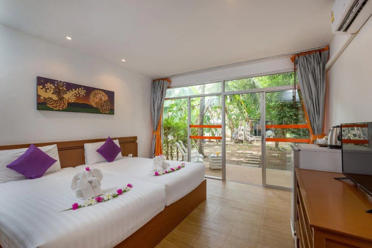 A hotel room with a bed, a desk, a TV, and a large window with curtains.
