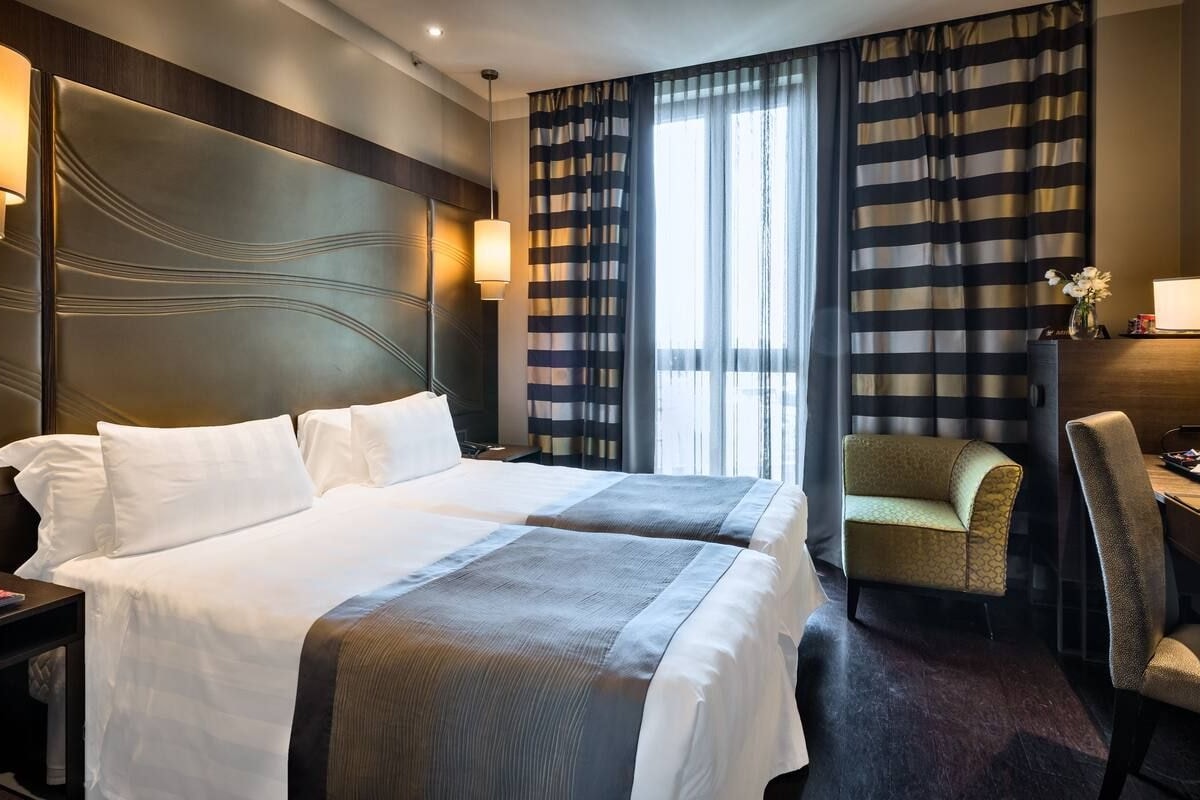Ett hotellrum med en stor säng, ett skrivbord och en stol.