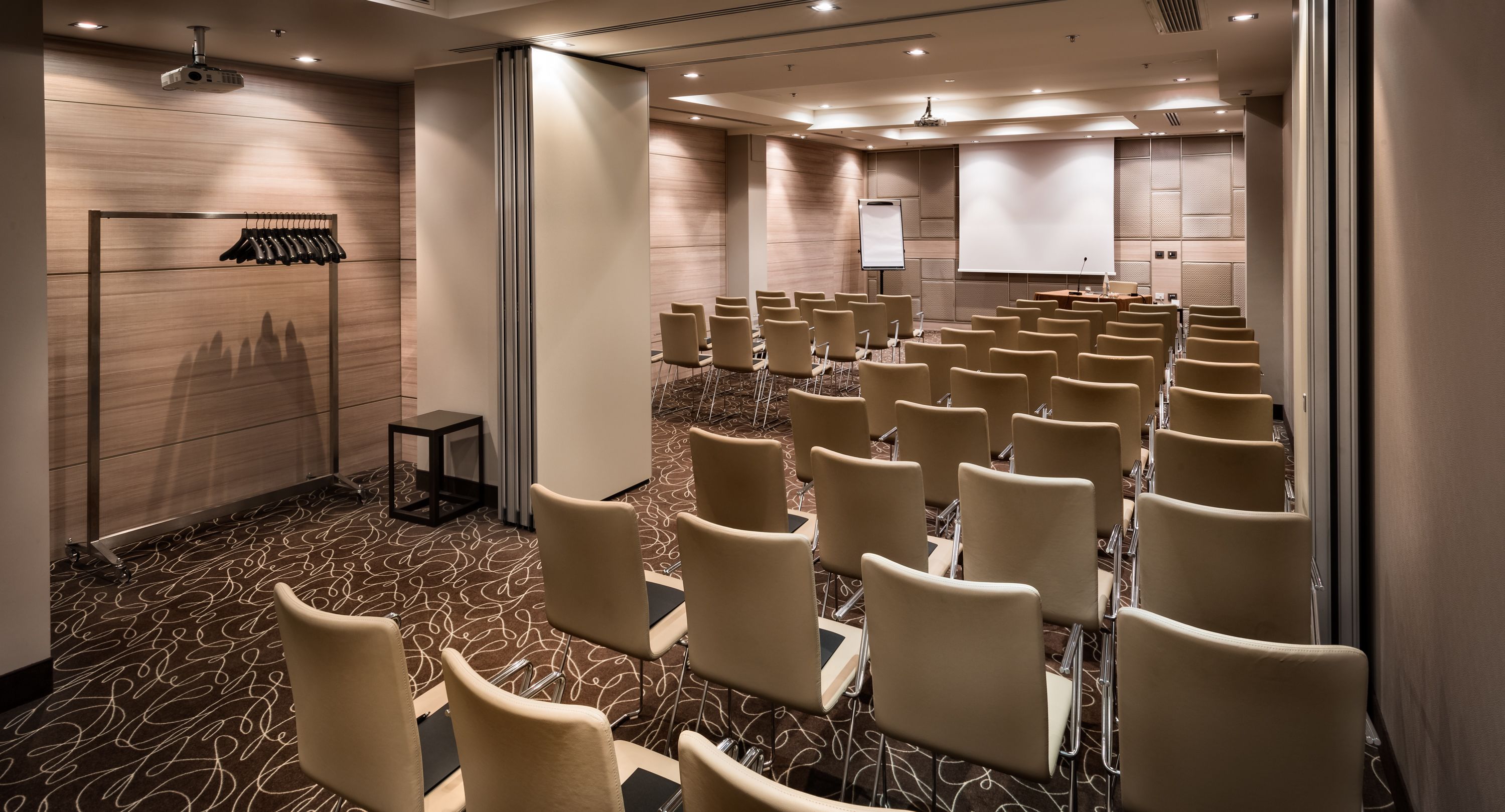 A conference room with rows of chairs, a projector, and a whiteboard.