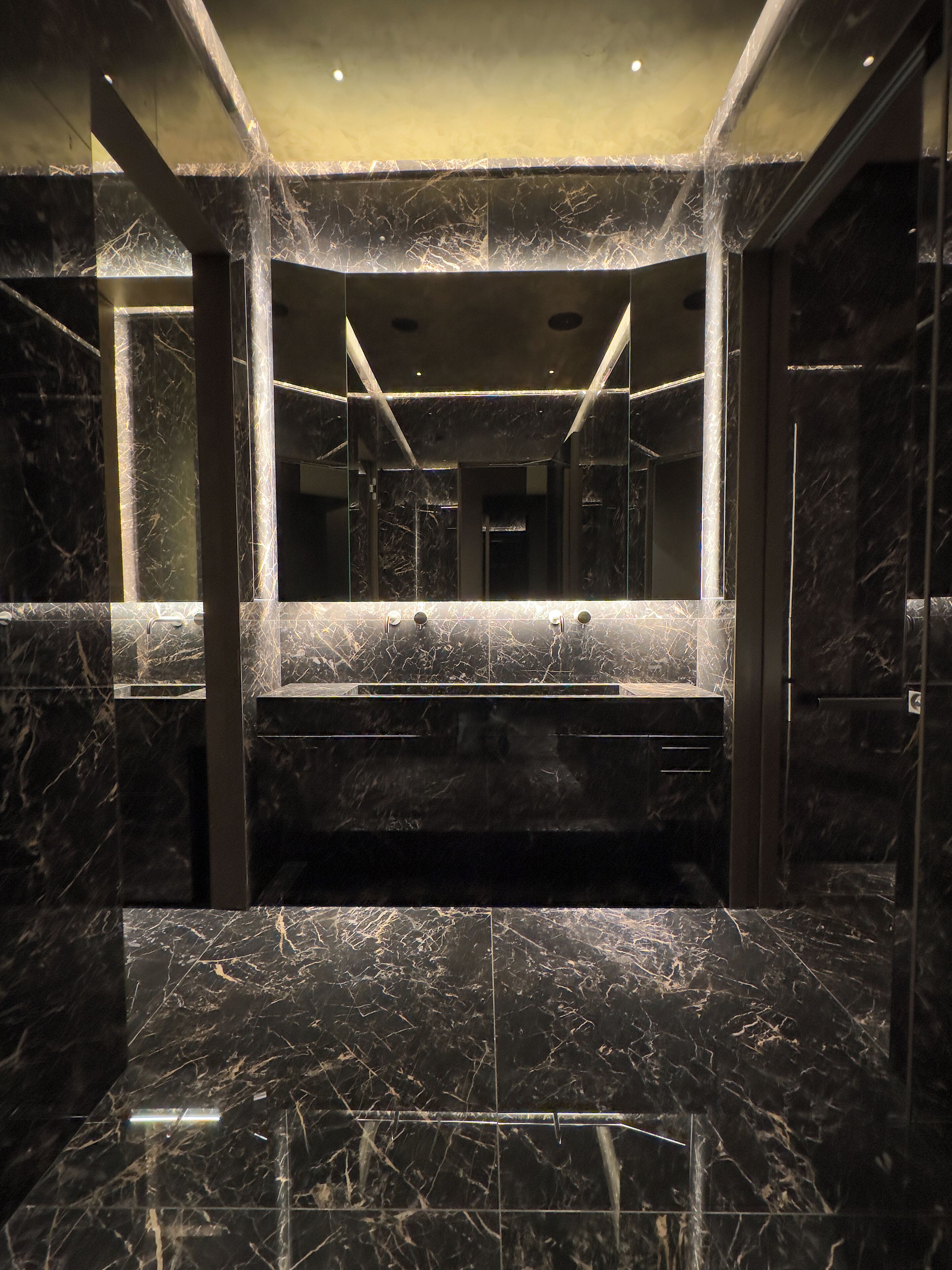 A modern bathroom with a large mirror, marble countertops, and a sleek design.