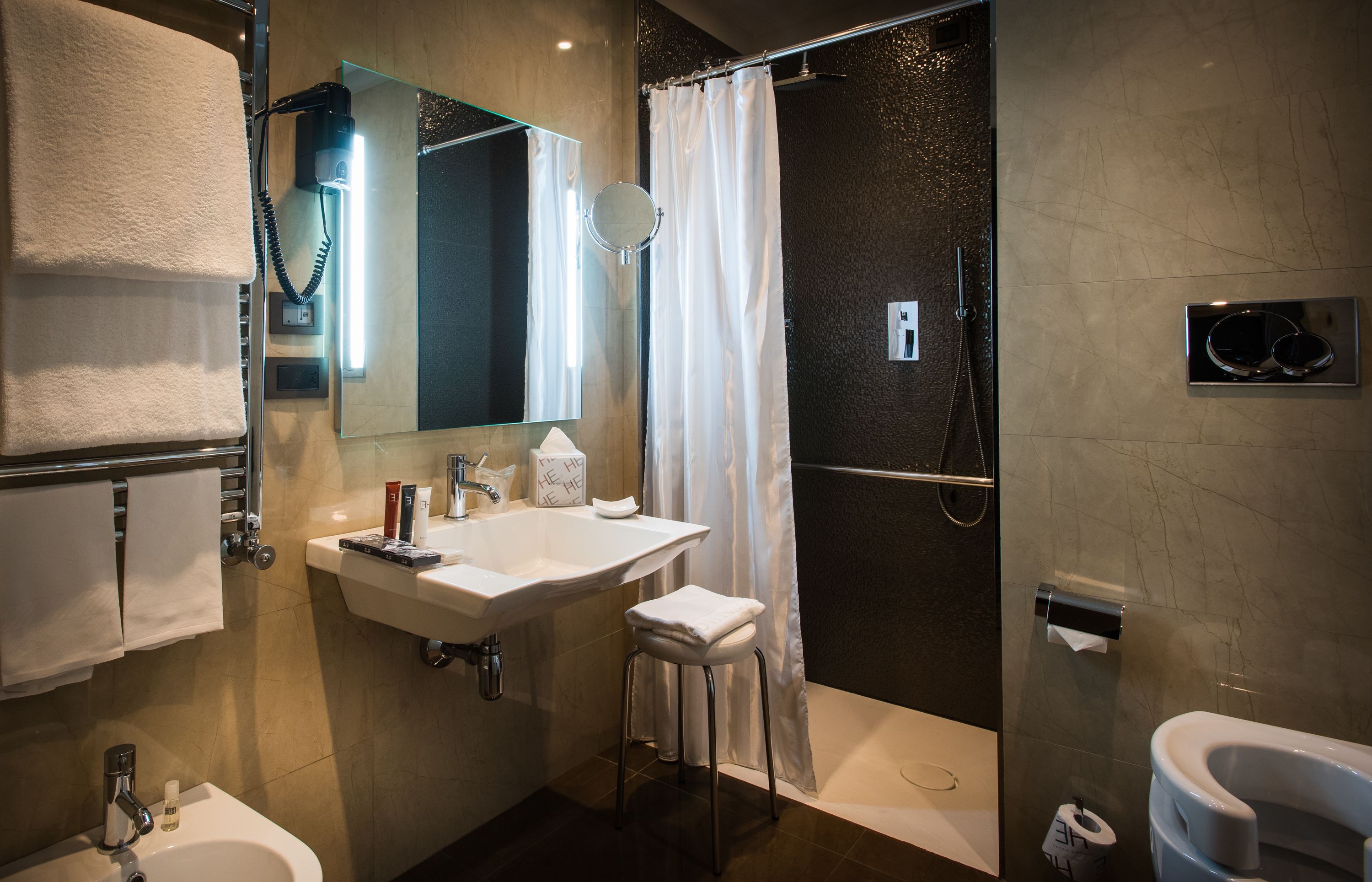 Un bagno moderno con lavandino, specchio, portasci, doccia e WC.