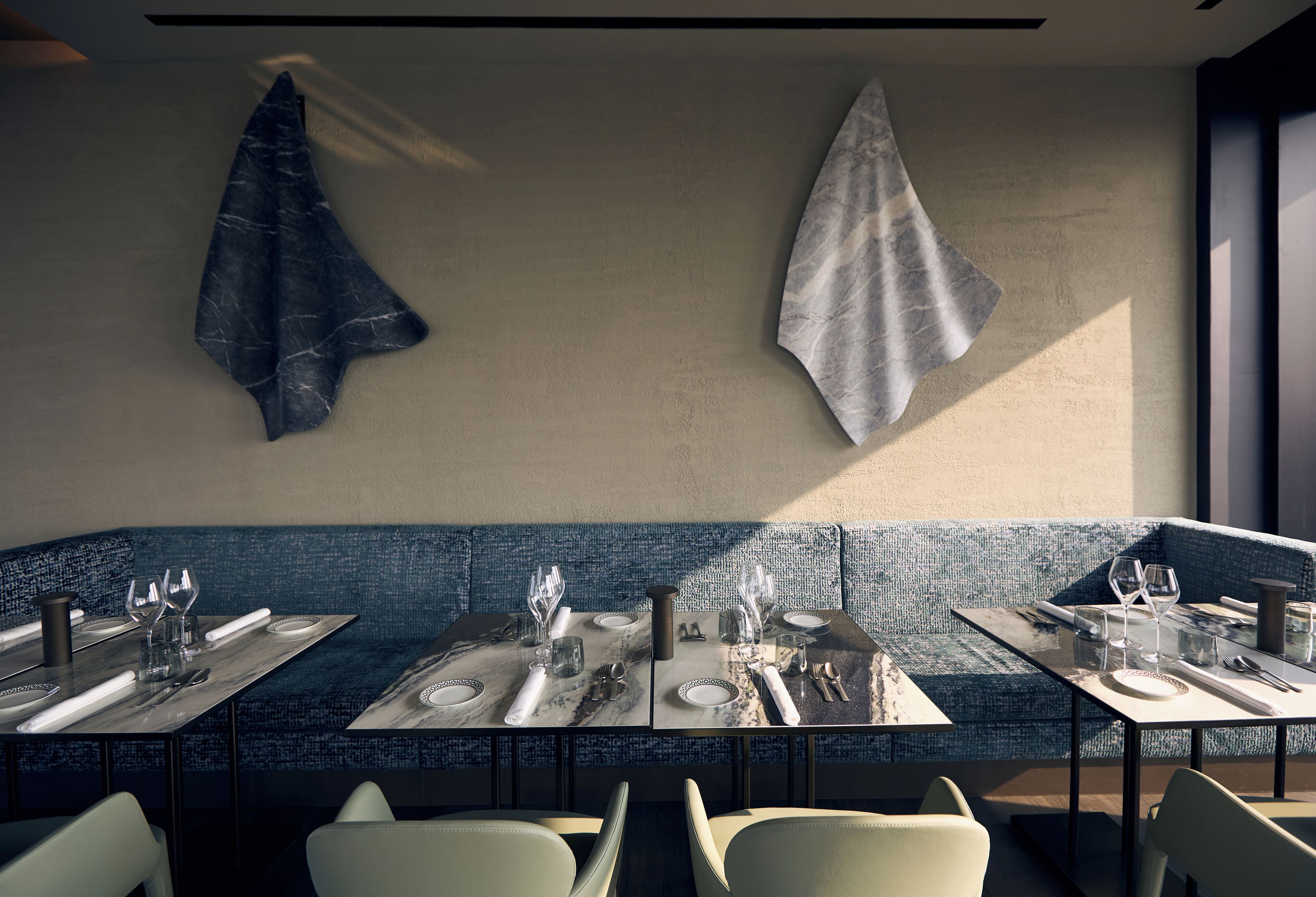 A restaurant with a modern interior, featuring a blue textured bench, marble-topped tables, and minimalist decor.