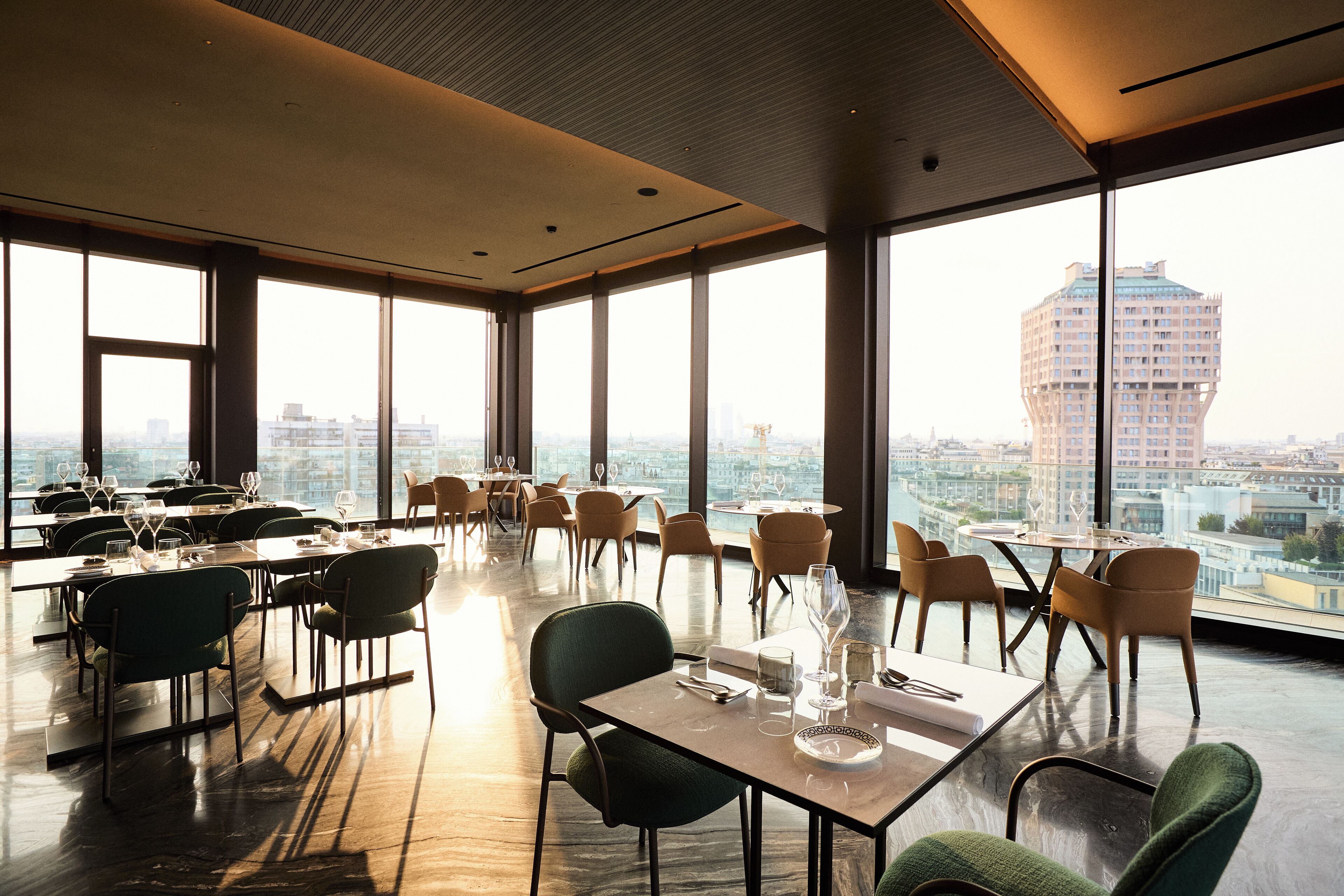 A modern dining area with large windows, tables set for dining, and a view of the cityscape.