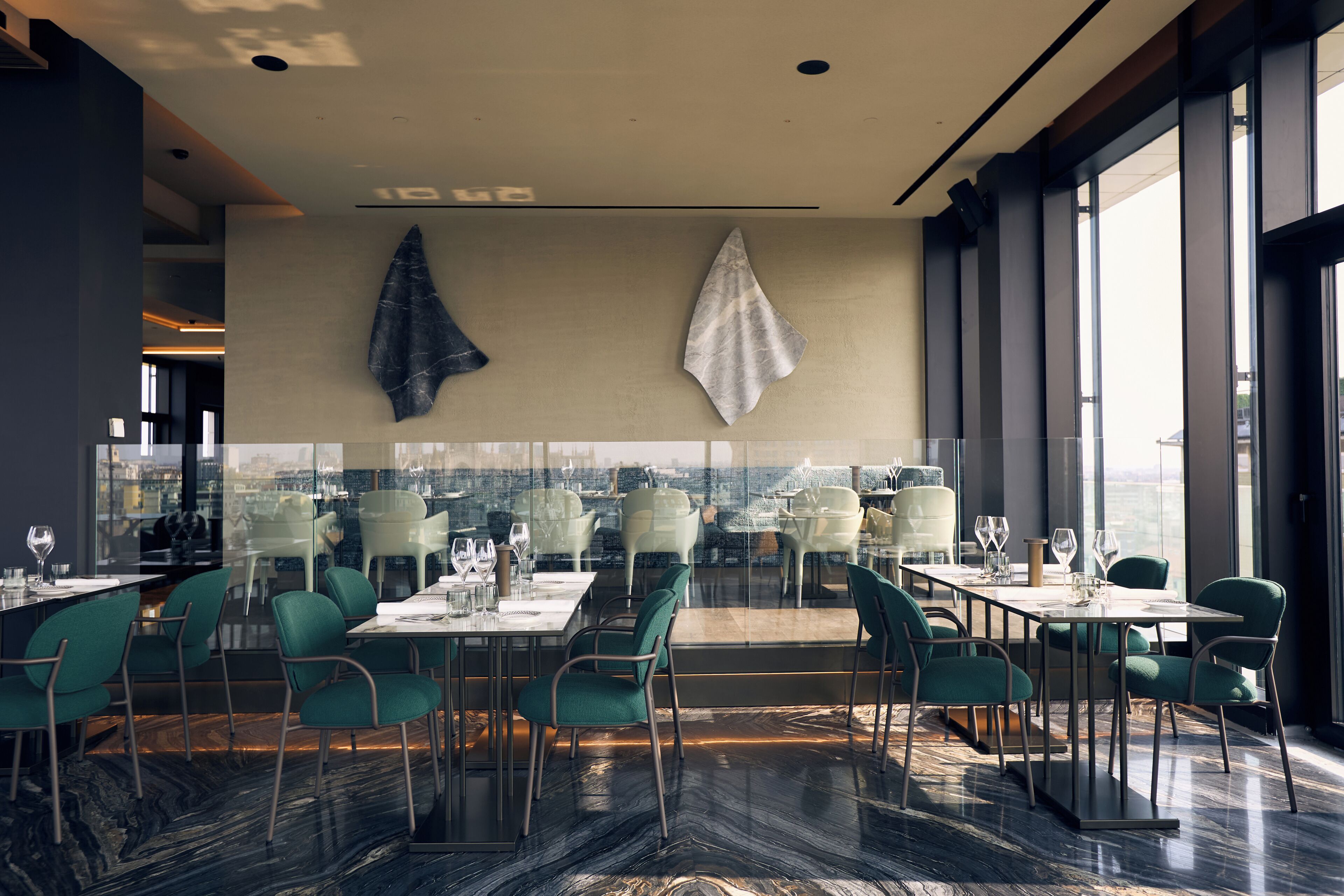 Un restaurante moderno con pared de vidrio, sillas verdes y suelo de mármol.