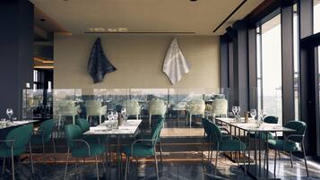 Un restaurant moderne avec un mur en verre, des chaises vertes et un sol en marbre.