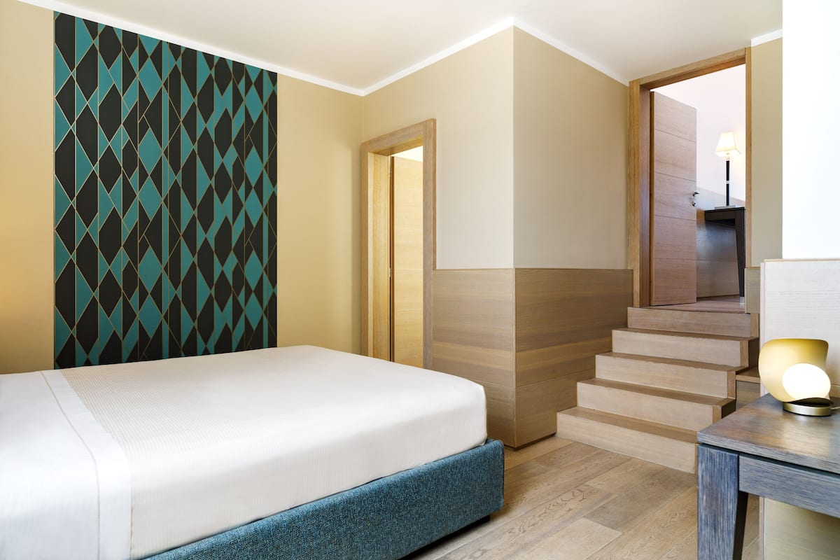 Ein Hotelzimmer mit einem Bett, einer Holztreppe und einem Schreibtisch mit Lampe.
