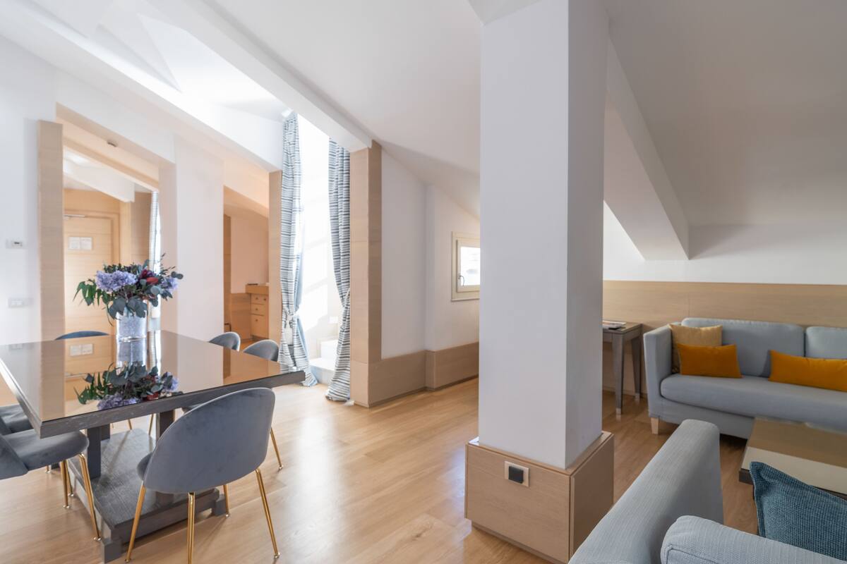Ein modernes Wohnzimmer mit einem grauen Sofa, einem Glastisch und einem grauen Sessel.