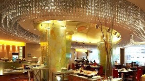 A dining area with a central glass partition, tables with food, and a decorative ceiling. - Ambassador Hotel Shenzhen (Shenzhen)